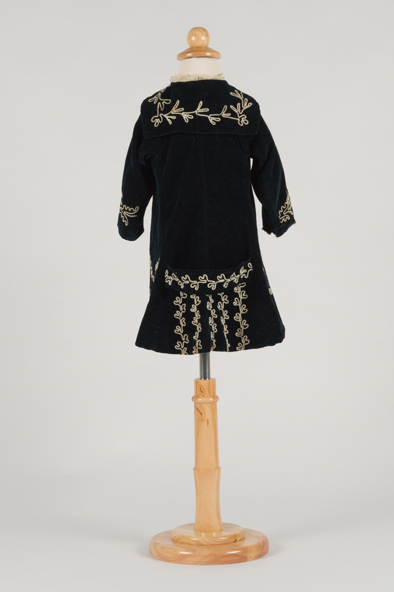 back of child's coat, it has a ring of embroidered flowers around the shoulders and detailing at the bottom