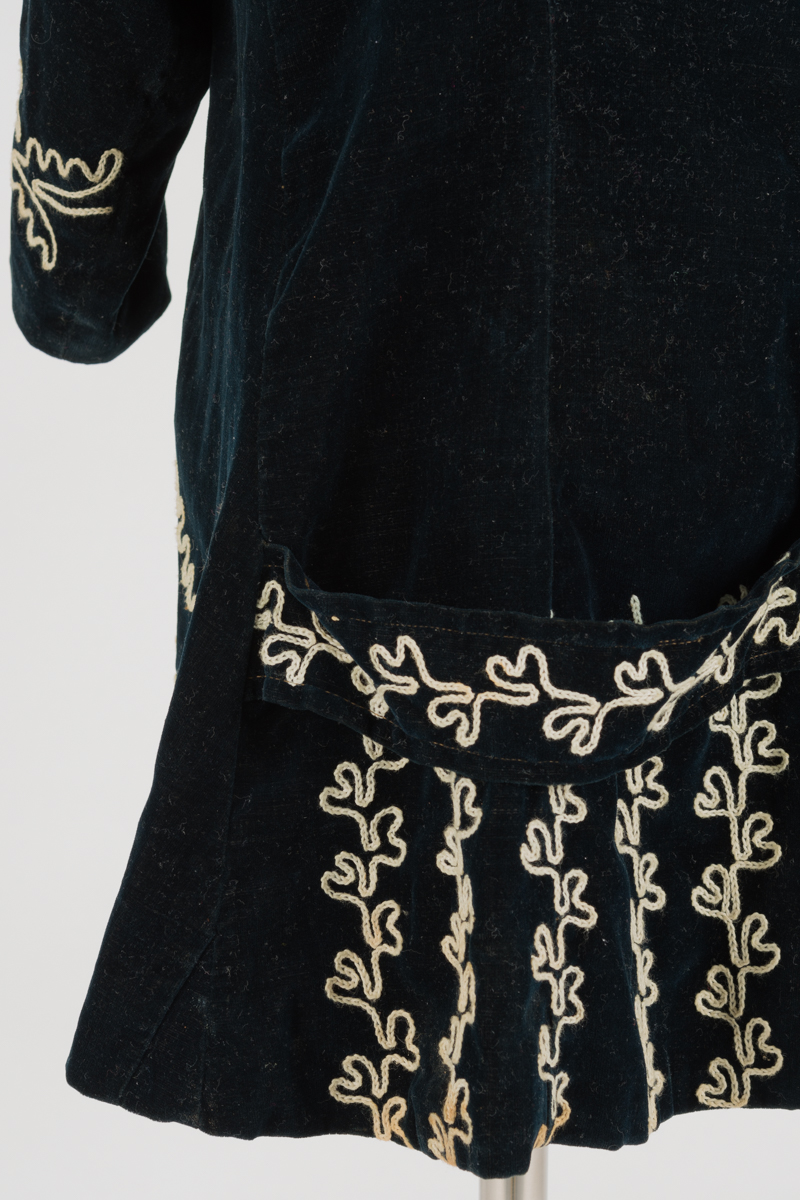 detail of the back of child's coat, simple embroidered leaves in lines adorn the bottom