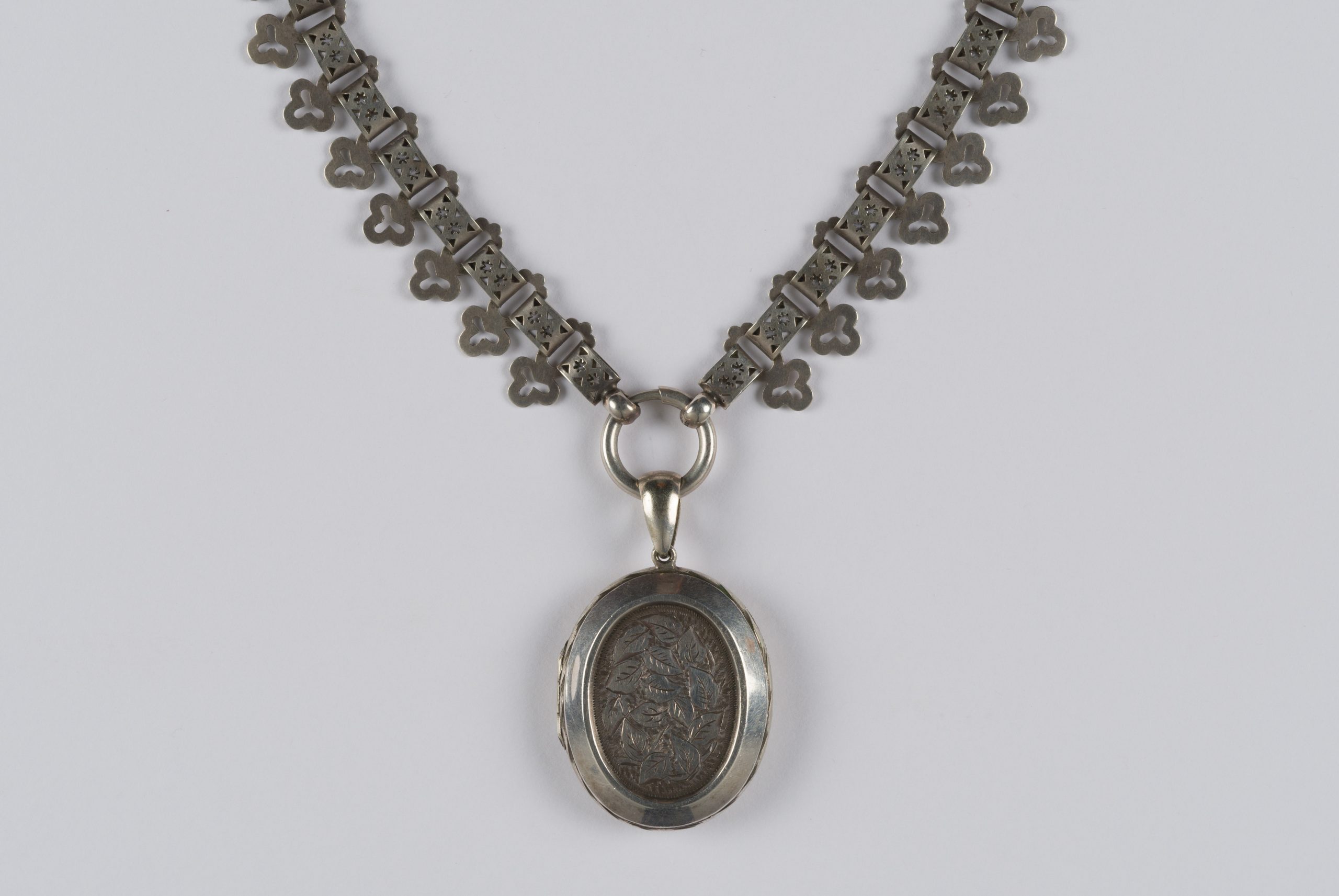 oval locket on a thick chain with clover-leaf design