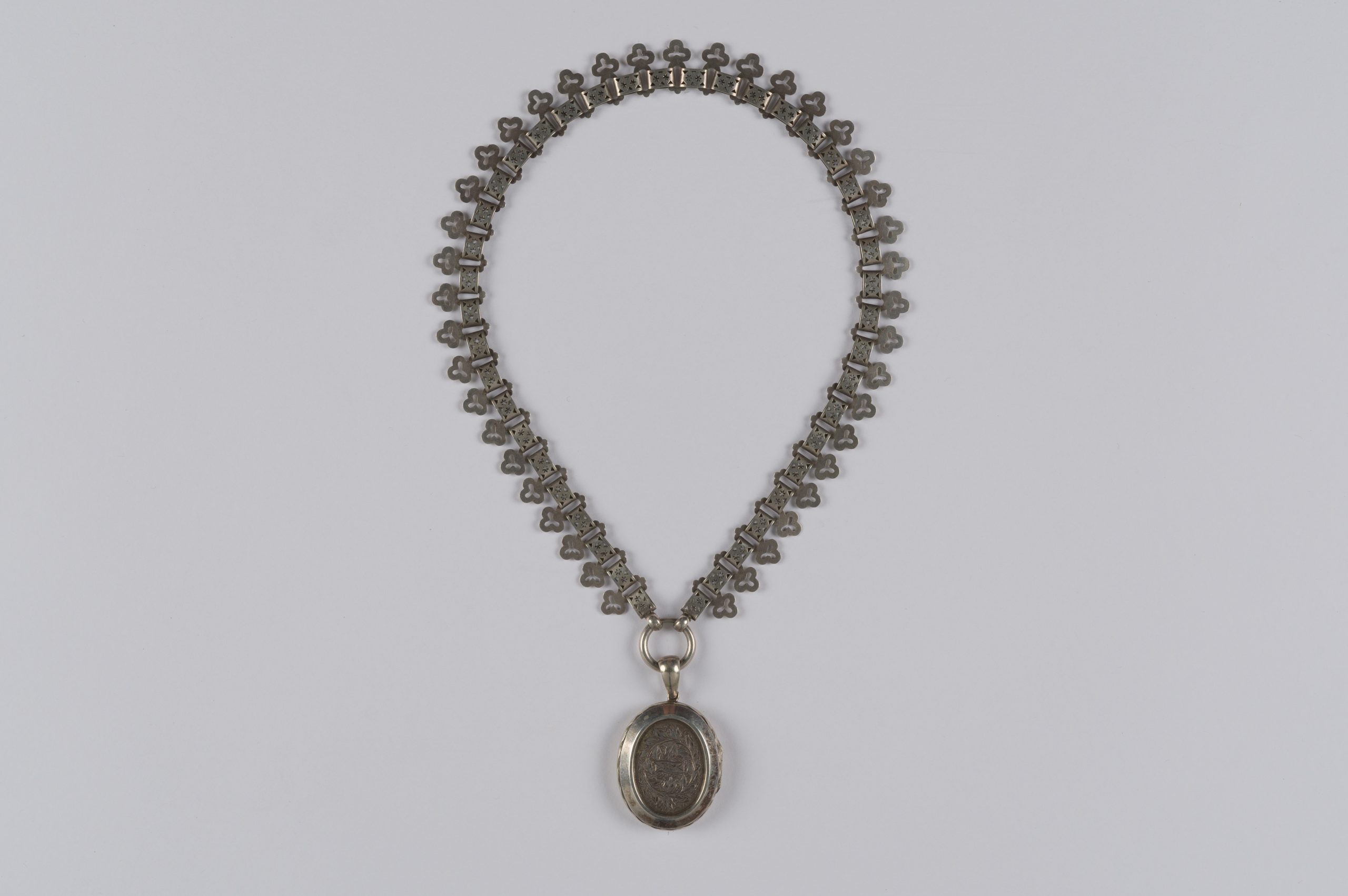 oval locket on a thick chain with clover-leaf design