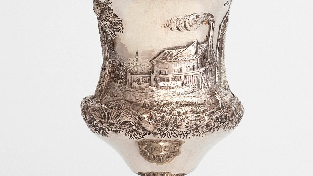 Silver goblet etched with a placid illustration of a refinery