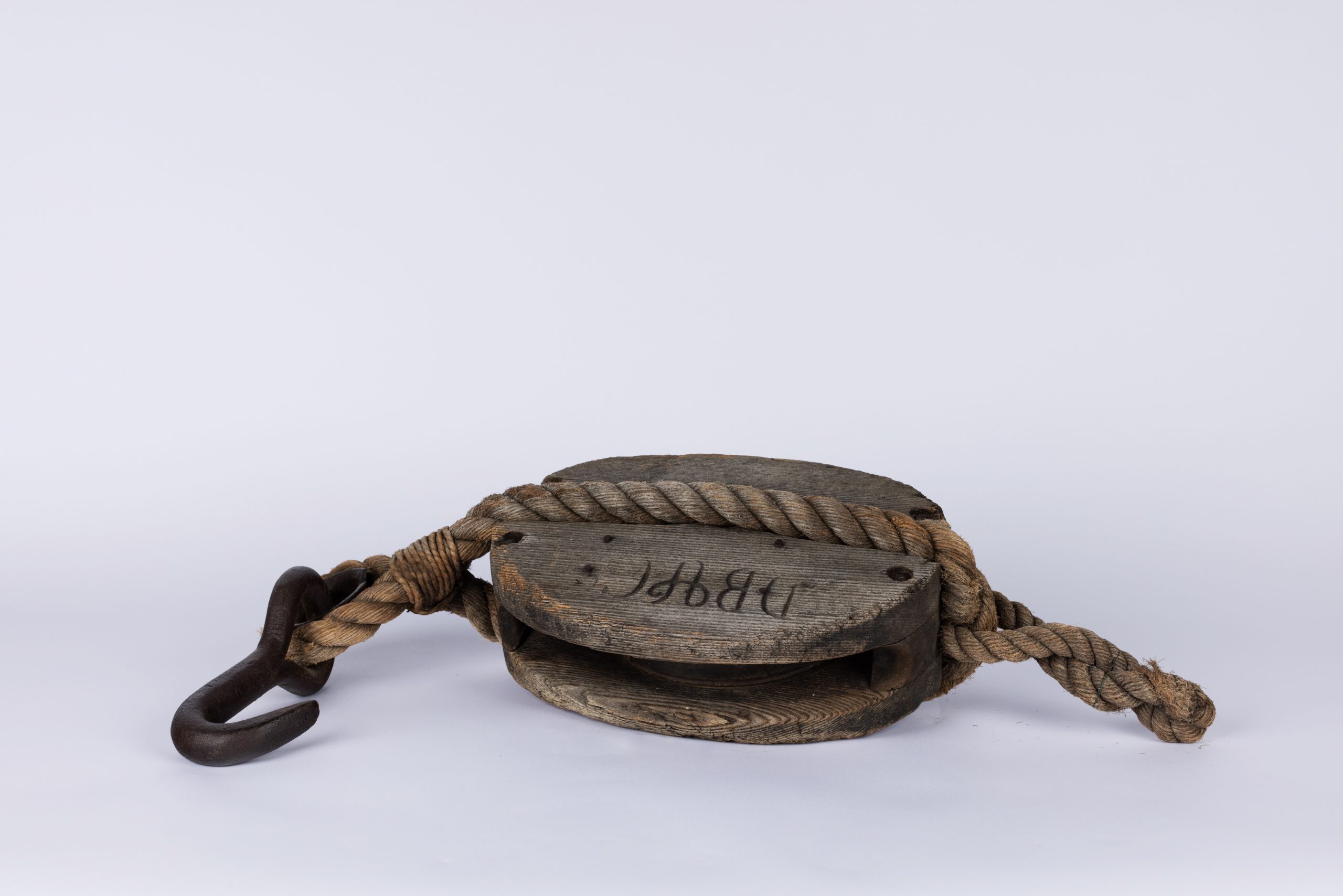 oval wooden block with a metal hook attached to one end, further secured by rope