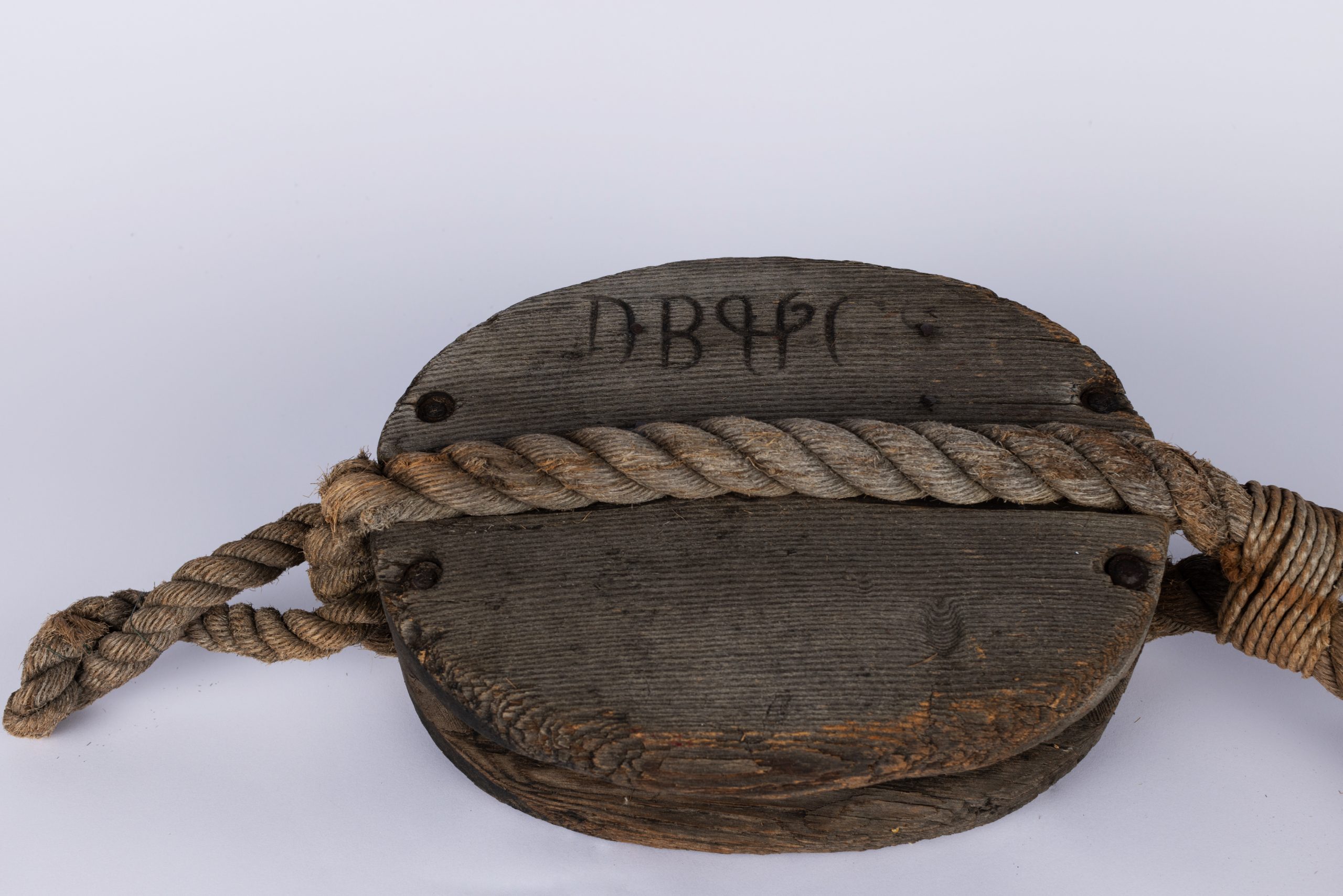 oval wooden block with a metal hook attached to one end, furthersecured by rope