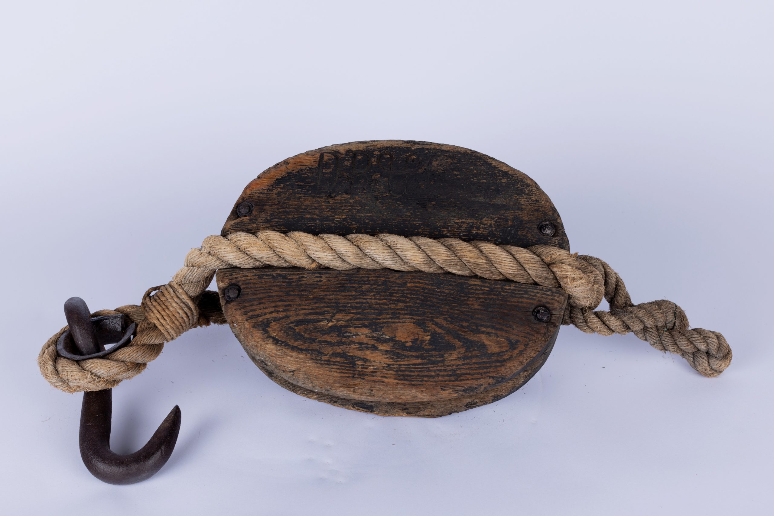 oval wooden block with a metal hook attached to one end, further secured by rope