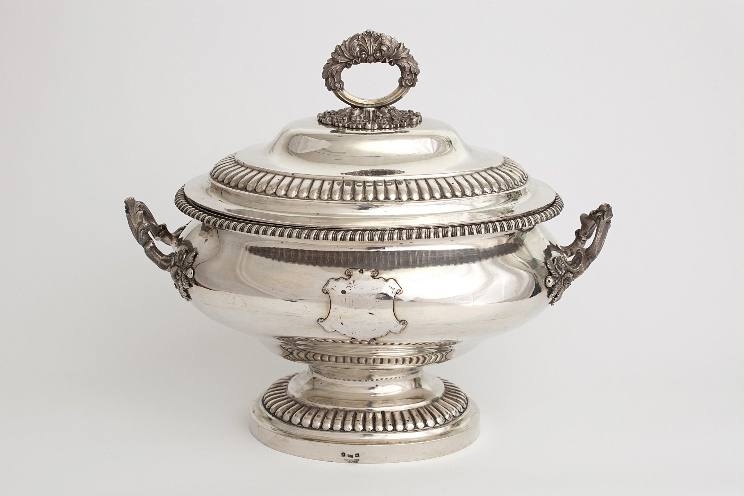 Ornate silver soup tureen embellished with petal shapes, scrolls, and floral fittings
