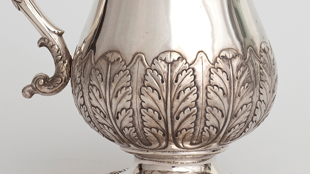 Close up of a silver tankard embellished with leafy design
