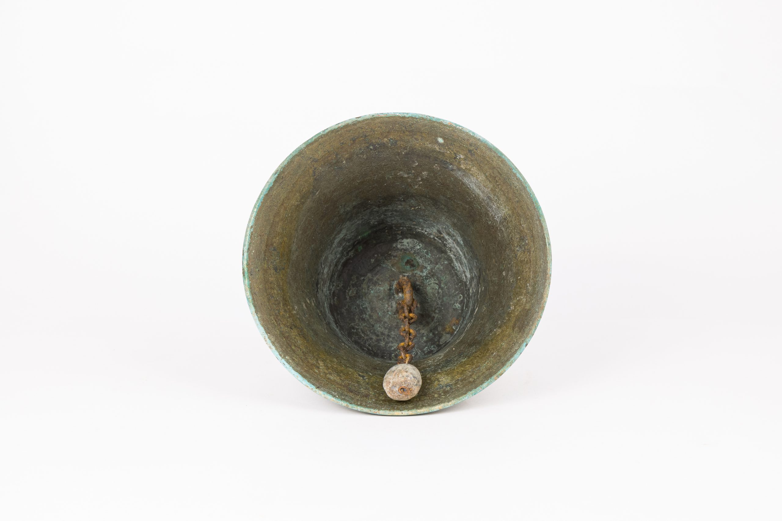 Underside of brassy metal bell with green oxidisation and a rusty ringer.