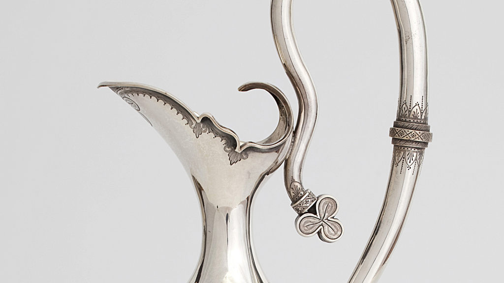 Close up of Elegant silver jug with pointed spout and slender handle which stretches upwards