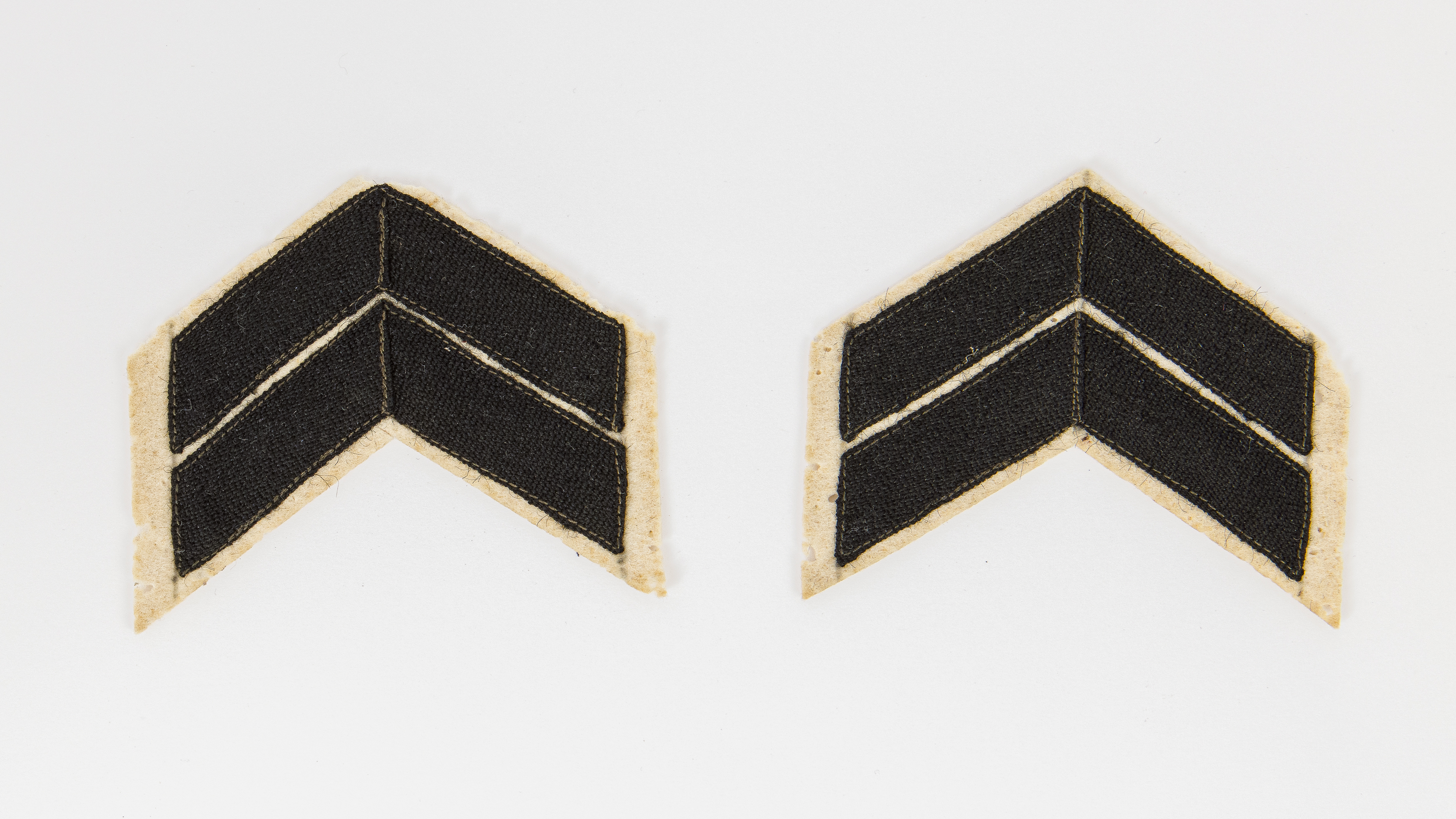 Two black and yellowed fabric patches shaped like the tops of arrows