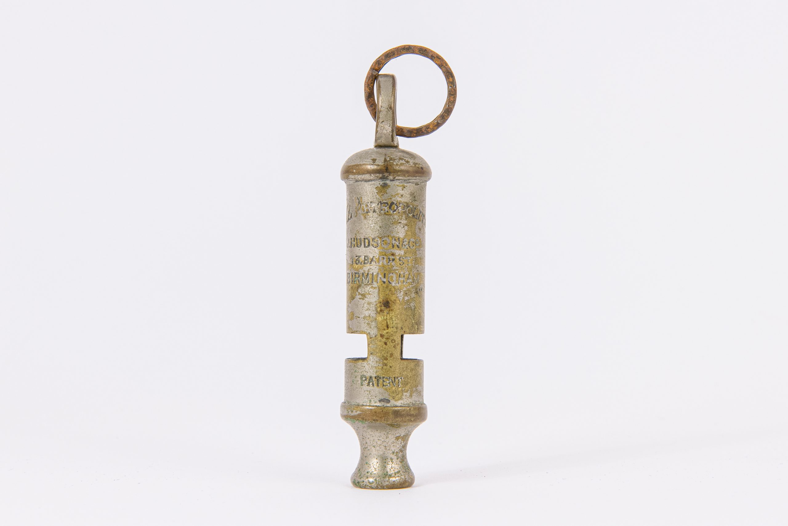 Tarnished, silver metal whistle, cylindrical in shape with a ring attachment. Engraved with "HUDSON AND CO." and "BIRMINGHAM."