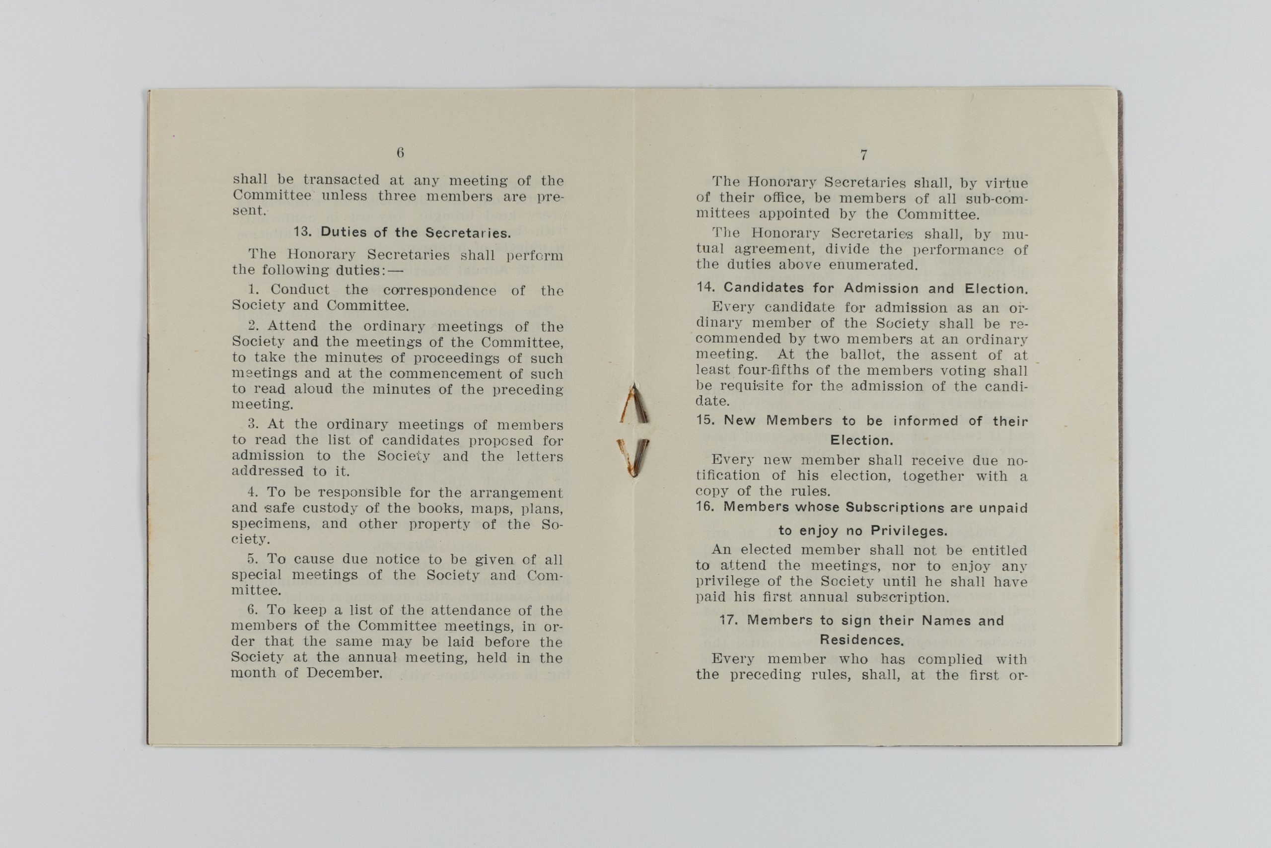 Printed book open to pages showcasing rules 12-17, including duties of secretaries, candidates for admission/election, new members to be informed of election, and signatures from members.