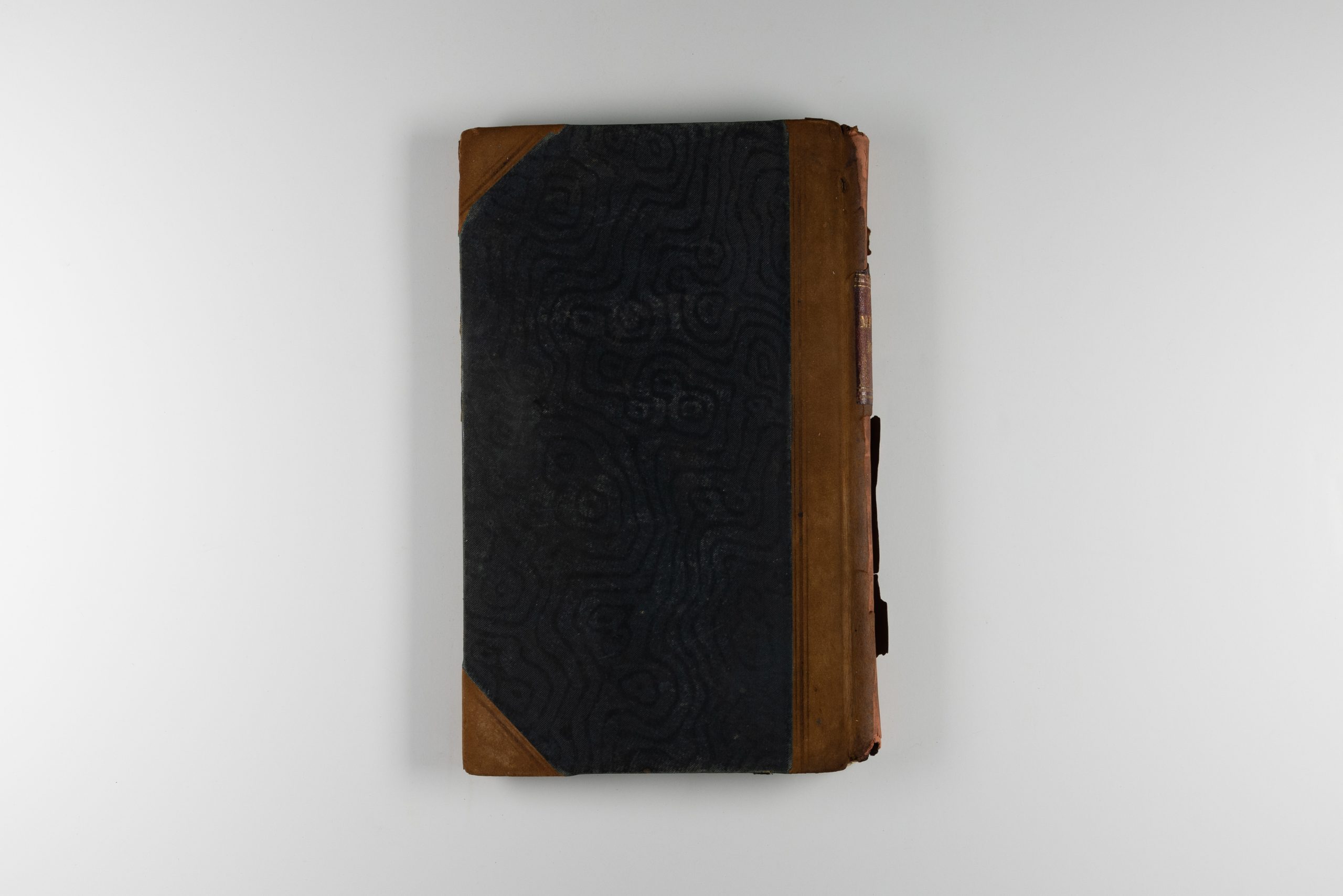 Back cover of a book, the cover is black with brown leather strips on the spine and corners.