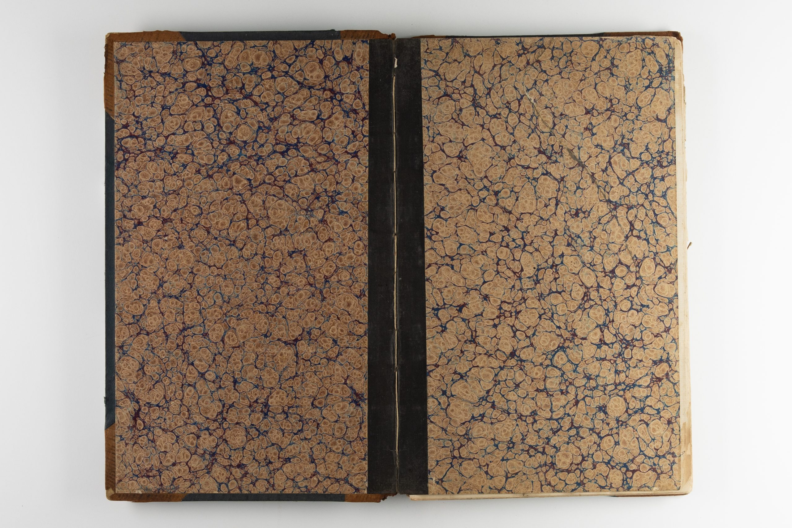 Book open to the binding pages; they are sepia, brown, and black in a marbled pattern