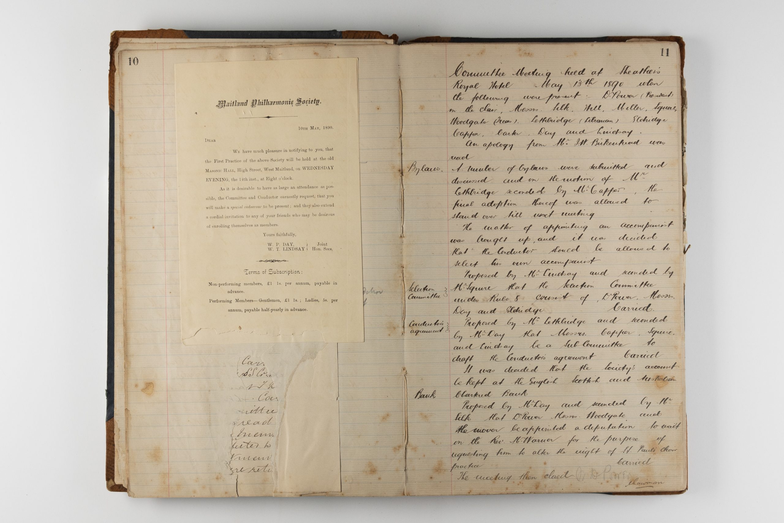 Open book with stained pages, handwritten cursive fills the right page and a letter advertising membership is stuck to the left page signed by W.P. Day and W.T. Lindsay