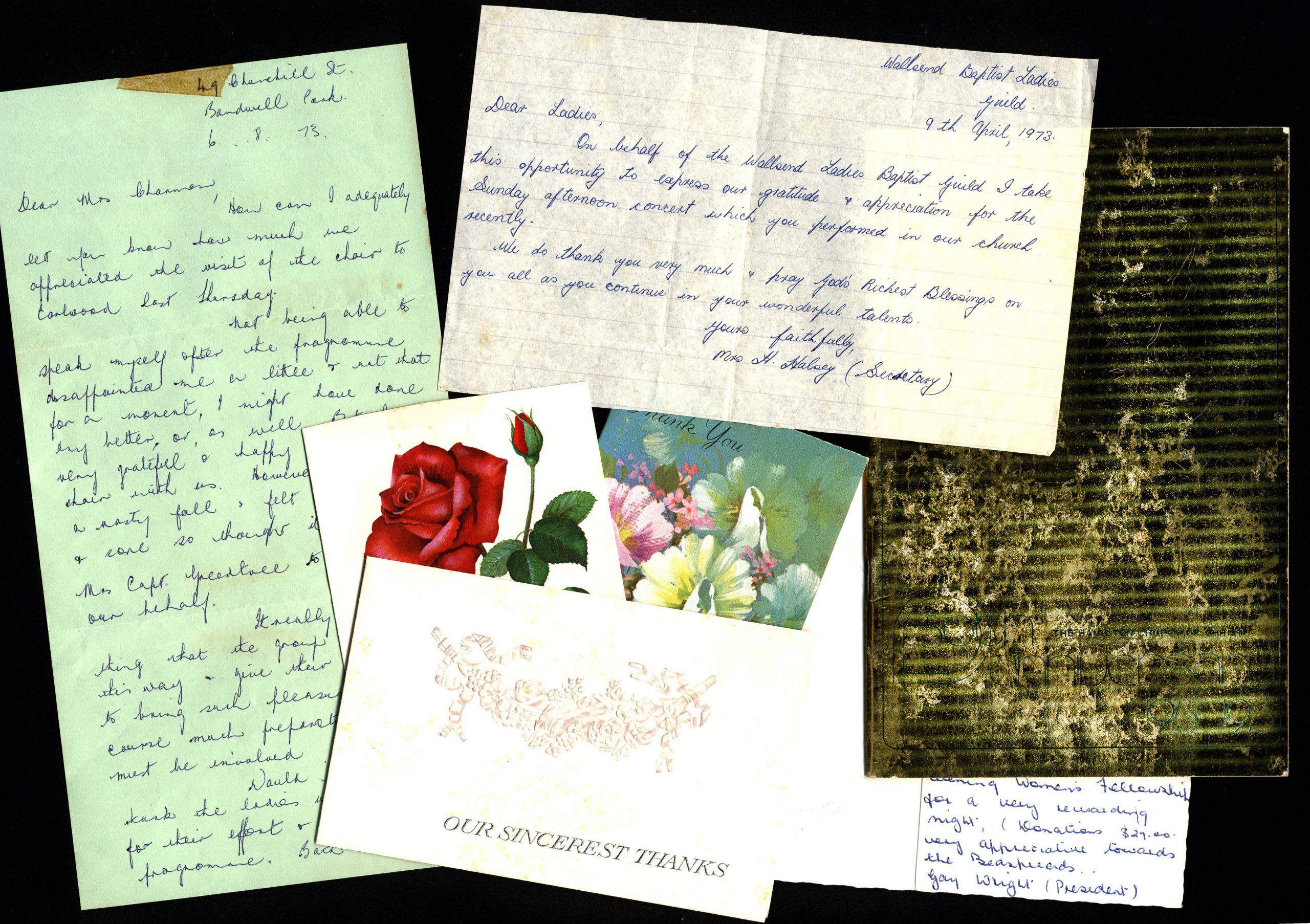 Assortes yellowed pages with handwritten cursive and postcards with illustrations of flowers.
