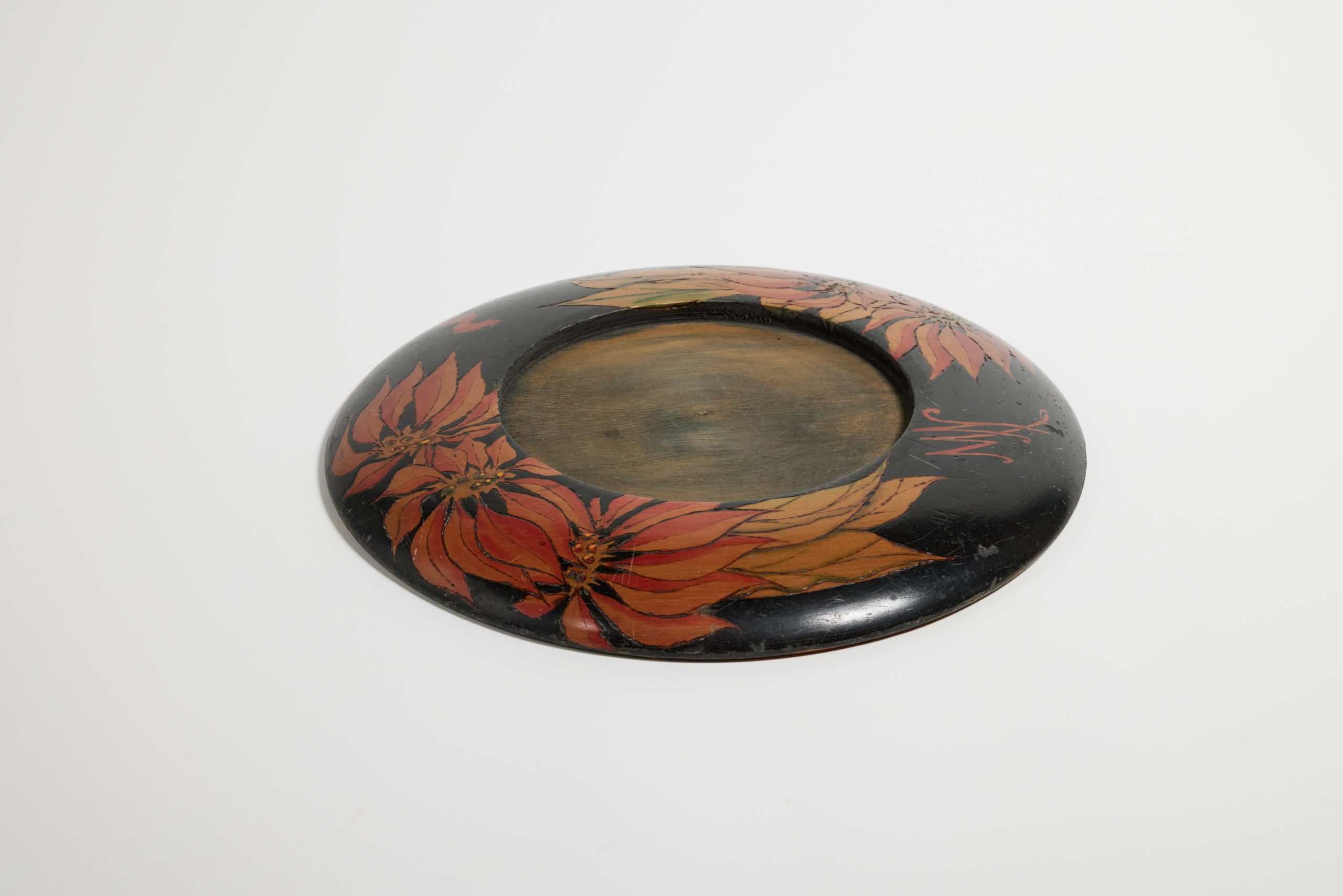 Circular breadboard without chopping board; design of poinsettia flowers burned into the wood