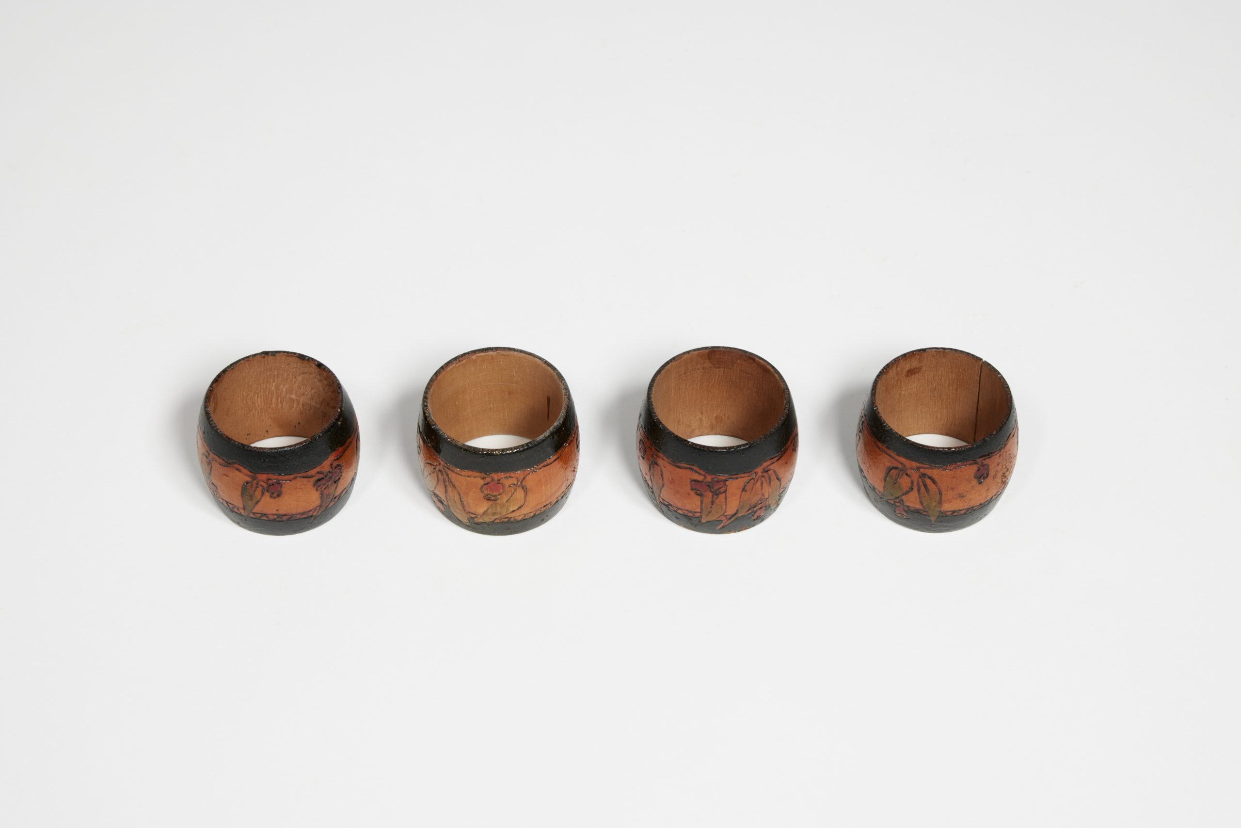 Four wooden napkin rings with gumnuts and black bands burned into them