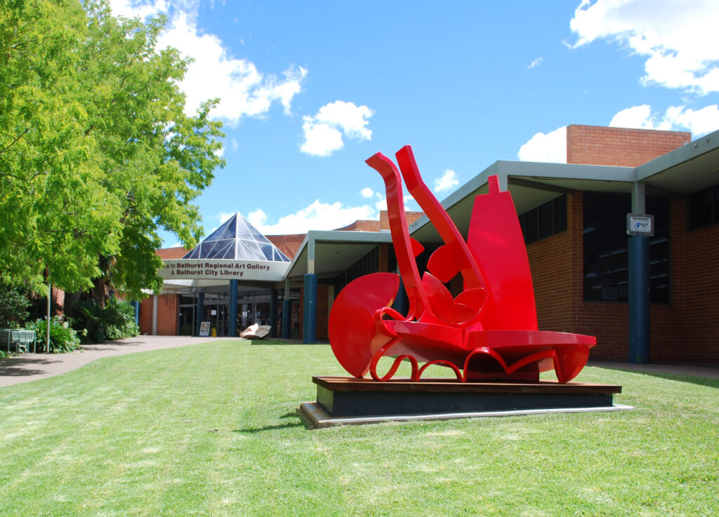 bright red outdoor installation sits on the grass outside the Bathurst Regional Art Gallery building
