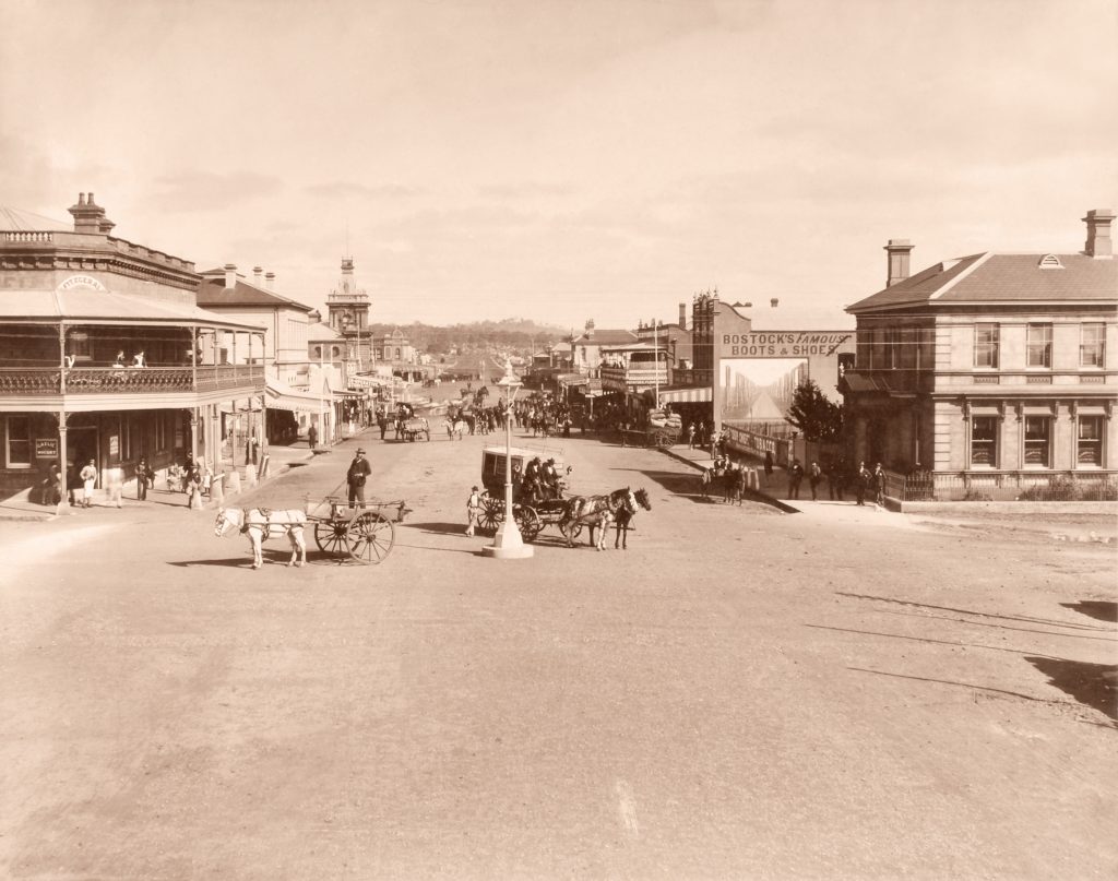sepia-tone photograph pf the main street of Glen Innes, it has wide dirt roads with horse-drawn carriages