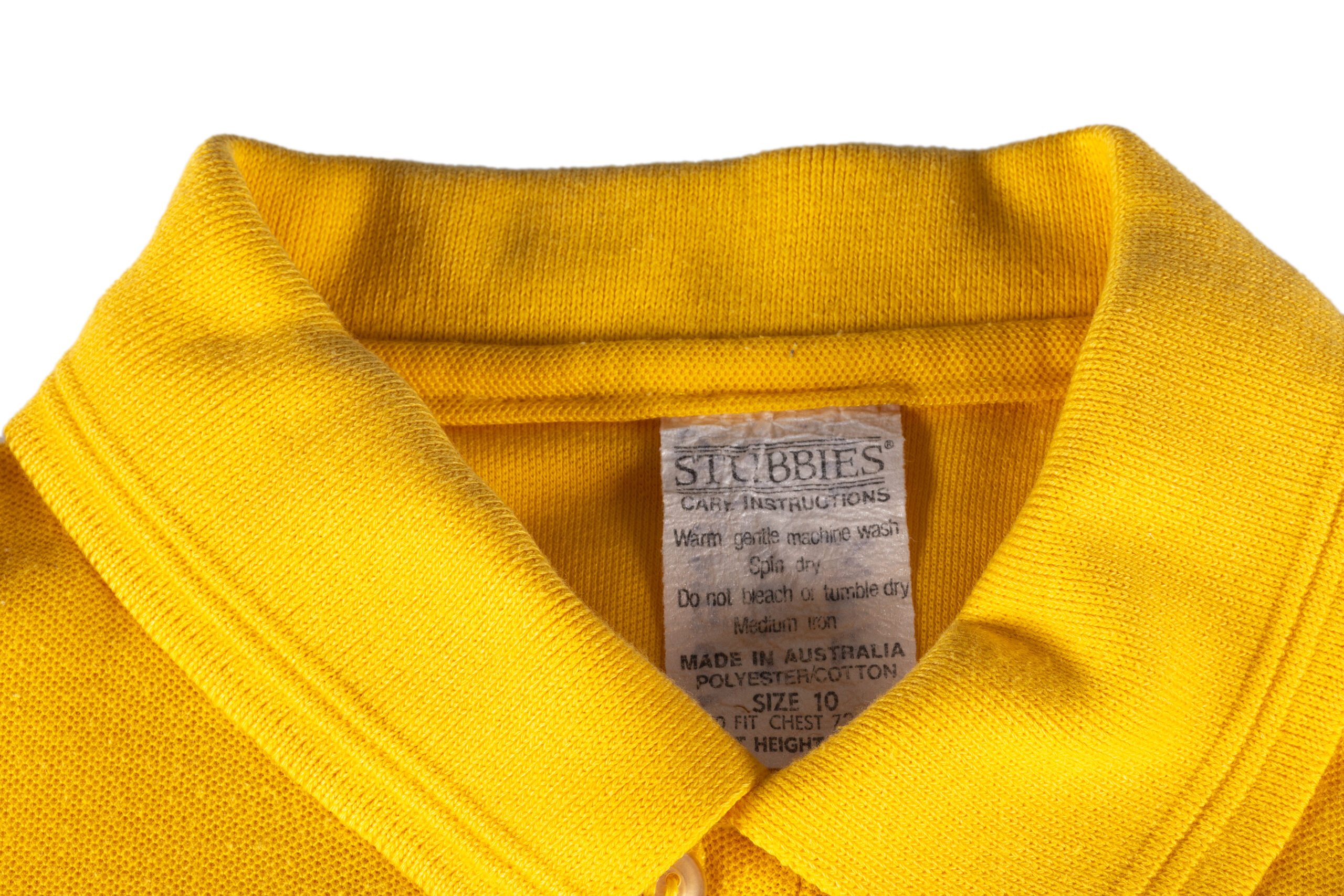 detail of yellow polo shirt collar, the tag is labelled STUBBIES and has care instructions